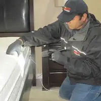 Bed bug inspection technician checking a mattress and bed frame for signs of infestation in Fort Worth, TX