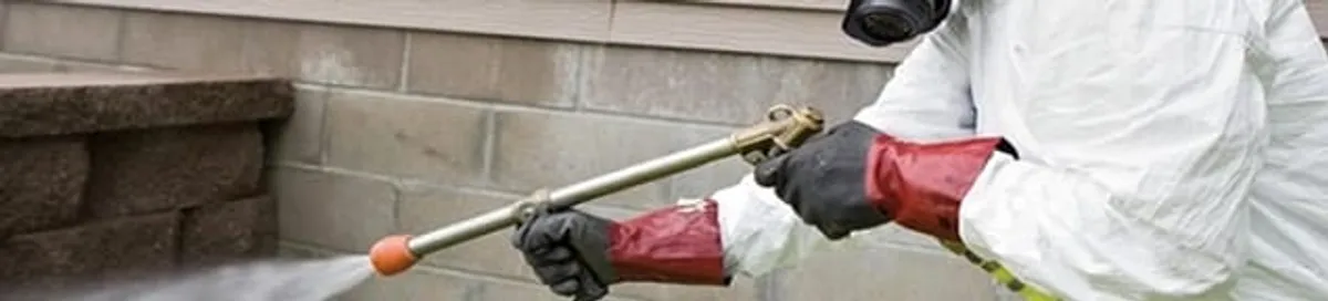 Pest control technician applying exterior insect treatment along a home foundation in Fort Worth, TX
