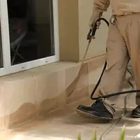 General pest control technician spraying exterior perimeter around a home in Fort Worth, TX