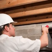 Termite inspection technician checking a basement wall and framing for termite activity in Fort Worth, TX
