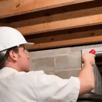 Termite inspection technician checking a basement wall and framing for termite activity in Fort Worth, TX